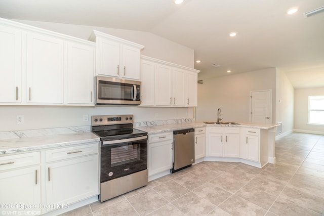 kitchen featuring stainless steel appliances, lofted ceiling, white cabinets, a sink, and a peninsula