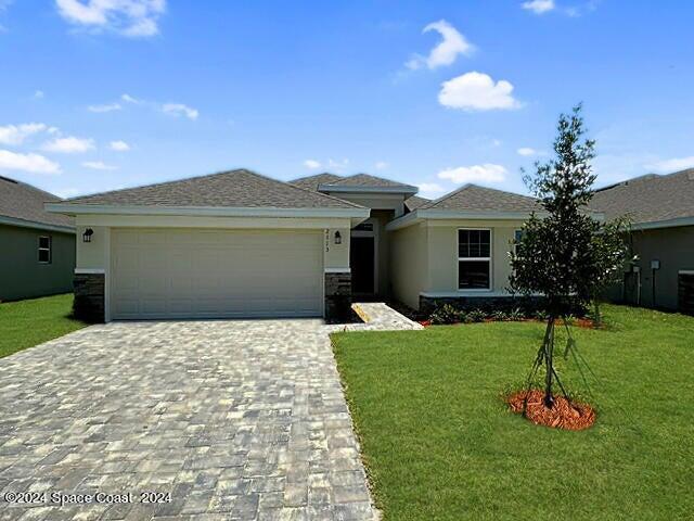 view of front of house featuring a garage, decorative driveway, a front lawn, and stucco siding