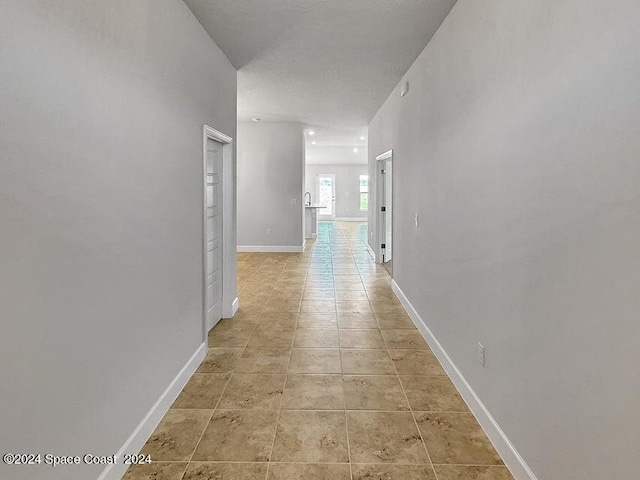 corridor with light tile patterned flooring and a textured ceiling