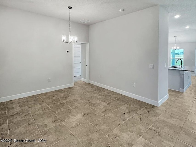 unfurnished dining area featuring a chandelier, recessed lighting, a sink, and baseboards