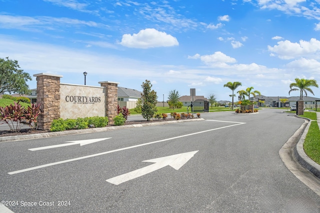 view of road featuring street lights, curbs, a gated entry, and a residential view