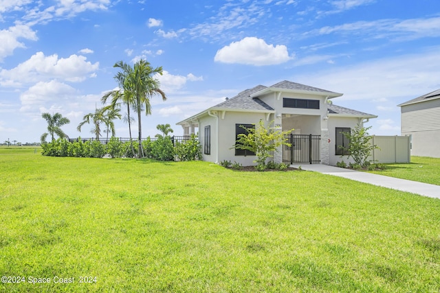 view of front of home featuring a shingled roof, fence, a gate, stucco siding, and a front lawn