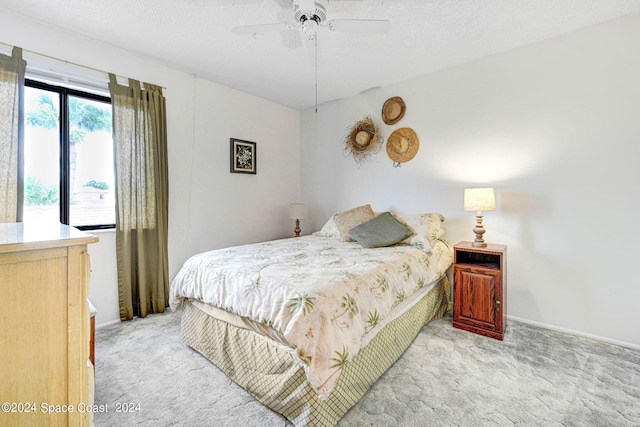 carpeted bedroom with ceiling fan and a textured ceiling