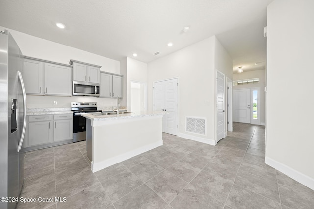 kitchen with appliances with stainless steel finishes, a kitchen island with sink, gray cabinetry, and sink