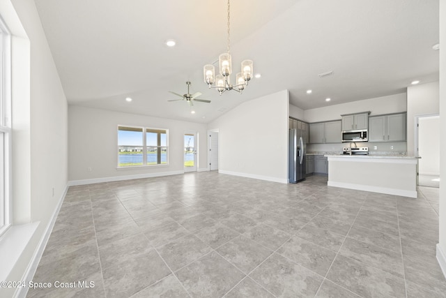 unfurnished living room with ceiling fan with notable chandelier, light tile patterned flooring, and lofted ceiling