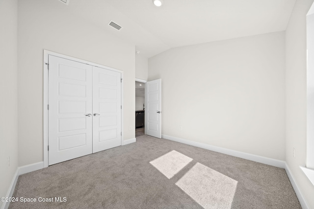 unfurnished bedroom with lofted ceiling, light carpet, and a closet