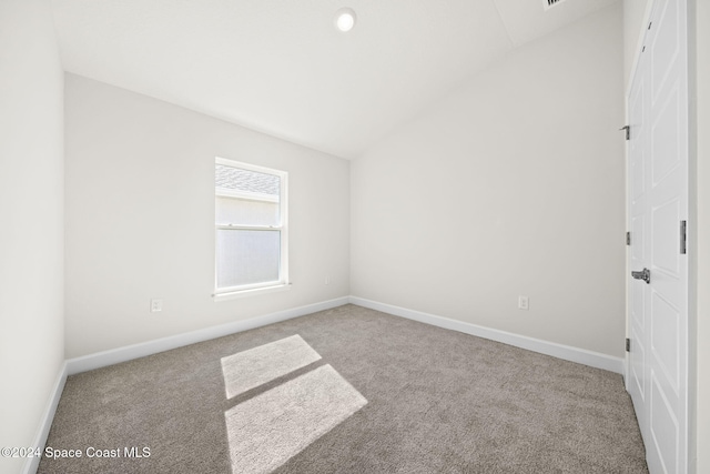 carpeted empty room with vaulted ceiling