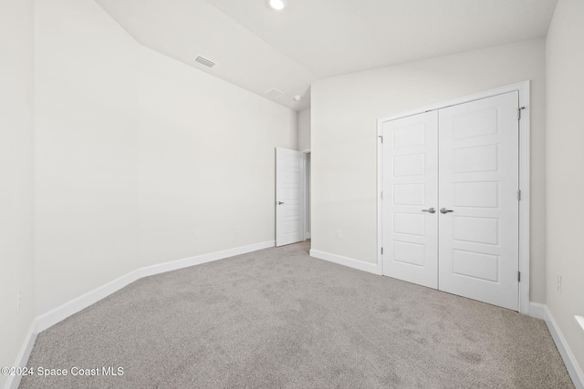 unfurnished bedroom with carpet flooring, a closet, and vaulted ceiling