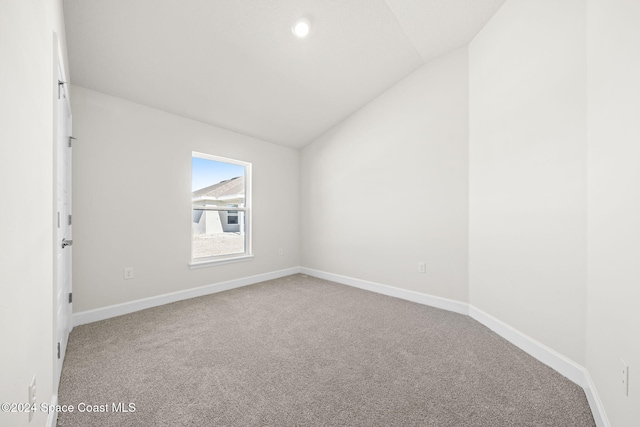 carpeted empty room featuring vaulted ceiling