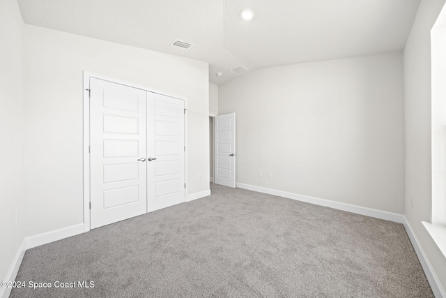 unfurnished bedroom with a closet, carpet floors, and vaulted ceiling