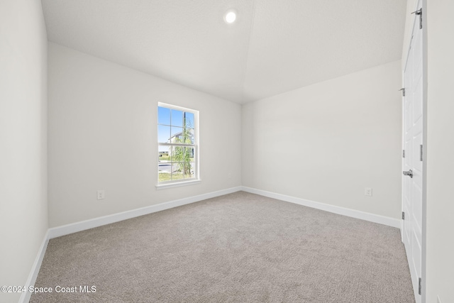 carpeted empty room featuring lofted ceiling