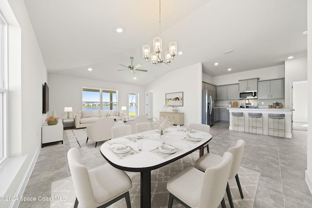 dining room featuring ceiling fan with notable chandelier and vaulted ceiling