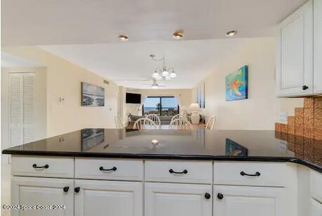 kitchen featuring white cabinets, backsplash, and a notable chandelier