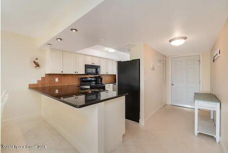 kitchen featuring black appliances, kitchen peninsula, backsplash, and white cabinets