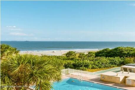 view of swimming pool with a water view and a view of the beach