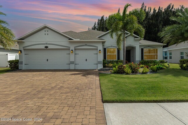 ranch-style home with a garage and a yard