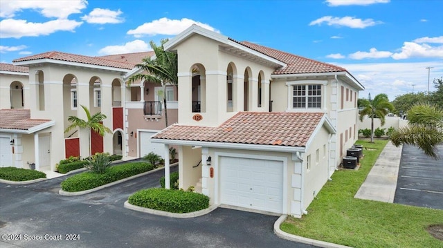 mediterranean / spanish-style house with a garage, stucco siding, driveway, and a tiled roof