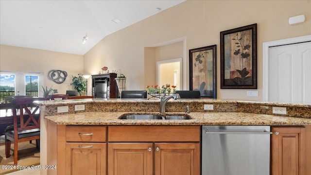 kitchen with lofted ceiling, dishwasher, light stone counters, and sink