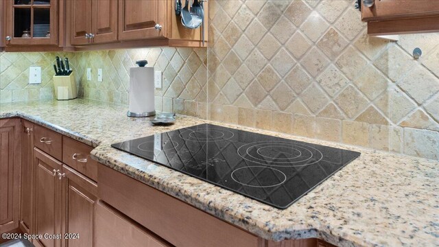 kitchen featuring black electric cooktop, light stone countertops, and tasteful backsplash