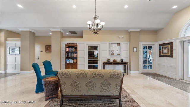 living room with plenty of natural light, a chandelier, and ornate columns