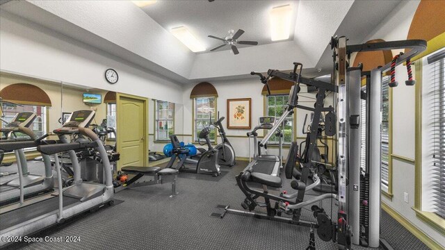 workout area with a textured ceiling, ceiling fan, and vaulted ceiling