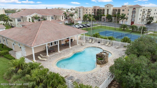 view of pool with tennis court and a patio