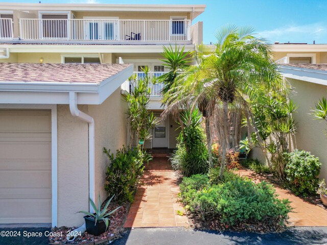 view of exterior entry featuring a balcony and a garage