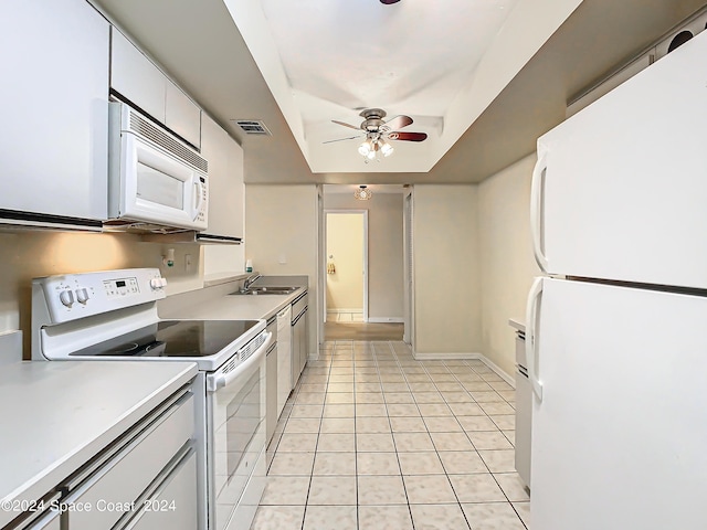 kitchen with light tile patterned floors, a raised ceiling, visible vents, a sink, and white appliances