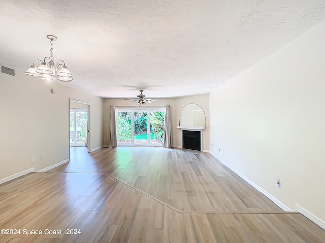 unfurnished living room with ceiling fan with notable chandelier, light hardwood / wood-style floors, and a textured ceiling