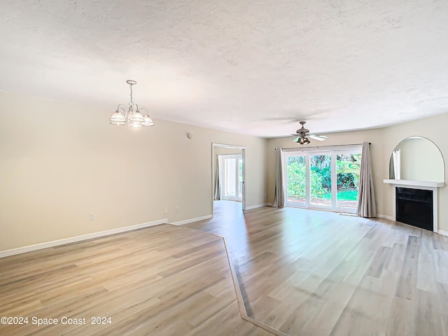 spare room featuring ceiling fan with notable chandelier, a textured ceiling, and light hardwood / wood-style floors