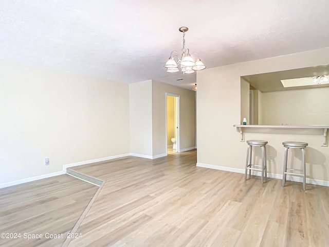 interior space featuring light wood-type flooring, an inviting chandelier, and baseboards