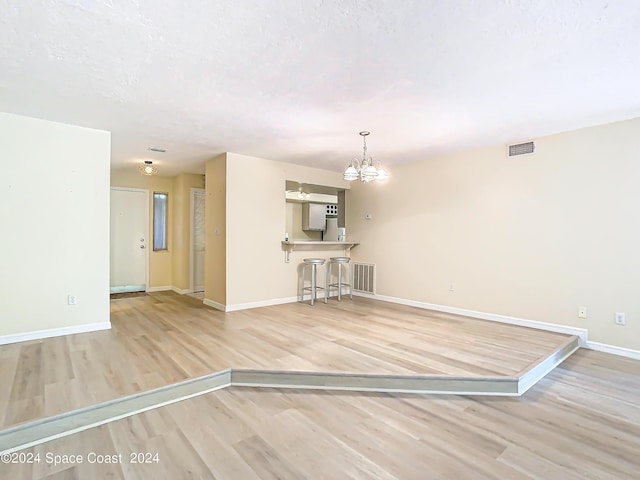 interior space with baseboards, visible vents, a chandelier, and wood finished floors