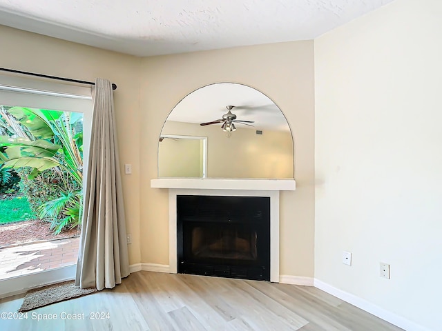 unfurnished living room with a fireplace, wood finished floors, a ceiling fan, and baseboards