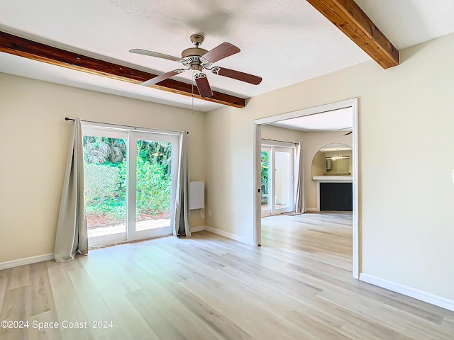 empty room featuring light wood finished floors, baseboards, and beam ceiling