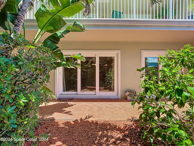 doorway to property with a patio area, a balcony, and stucco siding