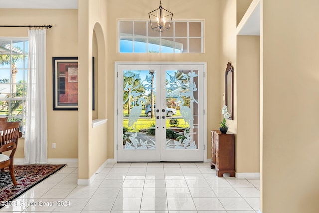 tiled foyer featuring a chandelier and french doors