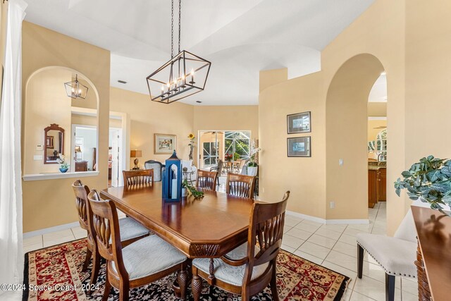 dining room with an inviting chandelier, light tile patterned floors, and lofted ceiling