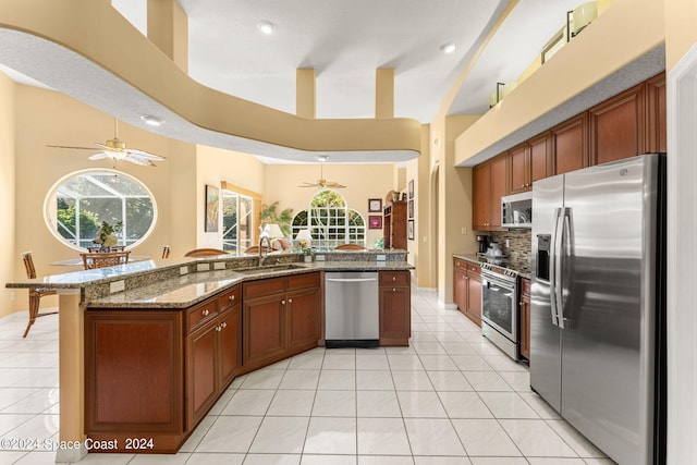 kitchen featuring light tile patterned floors, stone counters, appliances with stainless steel finishes, sink, and ceiling fan