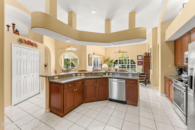 kitchen with appliances with stainless steel finishes, sink, dark stone counters, and ceiling fan