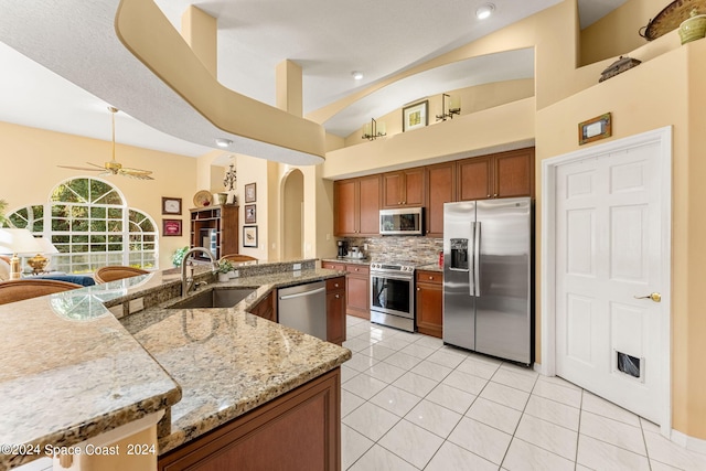 kitchen with stainless steel appliances, light stone counters, sink, ceiling fan, and light tile patterned flooring