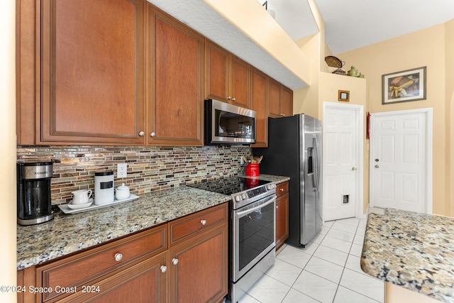 kitchen featuring light stone counters, light tile patterned floors, appliances with stainless steel finishes, and tasteful backsplash