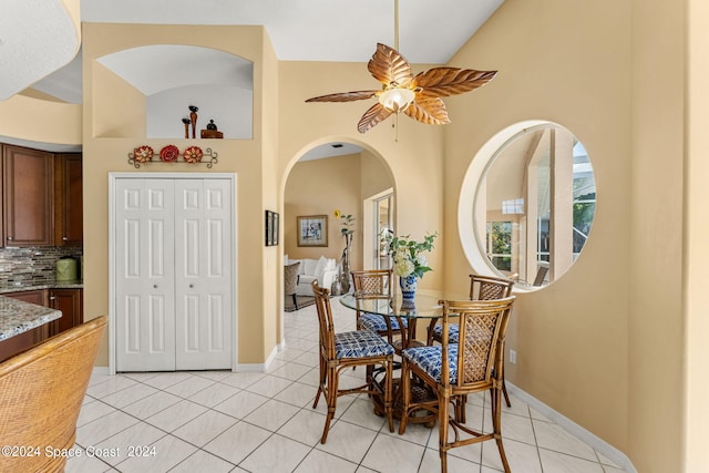 tiled dining room featuring high vaulted ceiling and ceiling fan