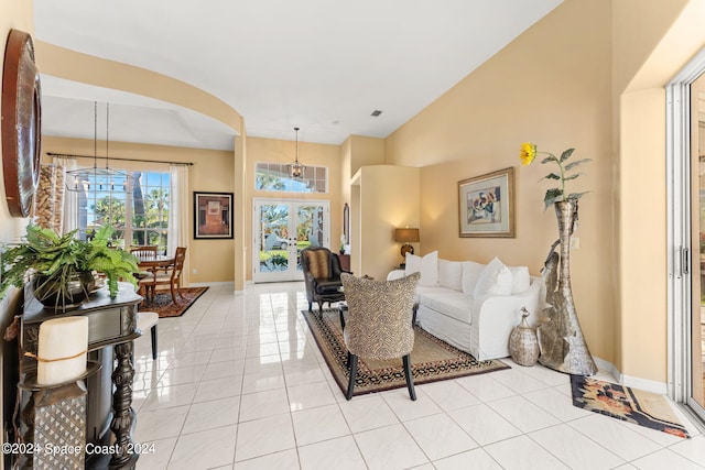 living room with lofted ceiling, light tile patterned floors, and an inviting chandelier