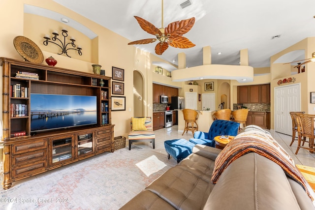 living room featuring a high ceiling, light tile patterned floors, and ceiling fan