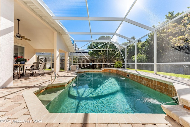 view of swimming pool featuring glass enclosure, pool water feature, ceiling fan, and a patio area