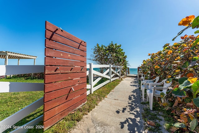 view of gate featuring a pergola and a water view