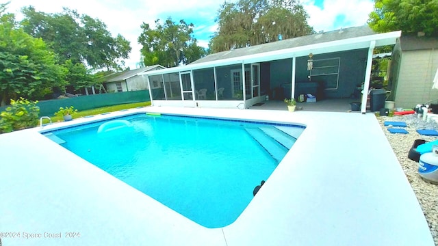 view of swimming pool featuring a patio and a sunroom