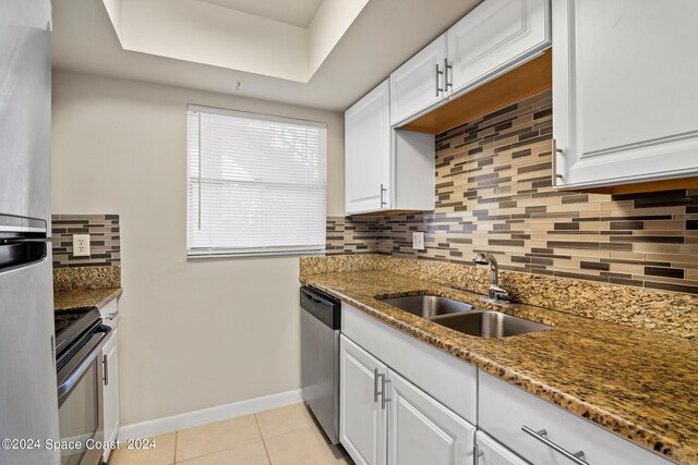 kitchen with stainless steel appliances, sink, dark stone countertops, and white cabinetry