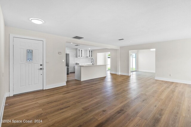 unfurnished living room featuring sink and dark hardwood / wood-style flooring