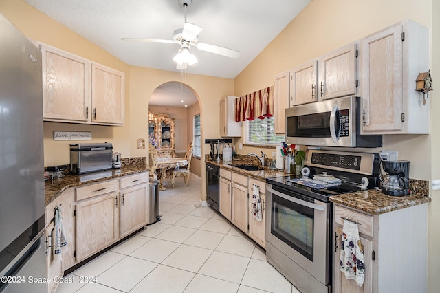 kitchen with dark stone countertops, appliances with stainless steel finishes, sink, lofted ceiling, and ceiling fan